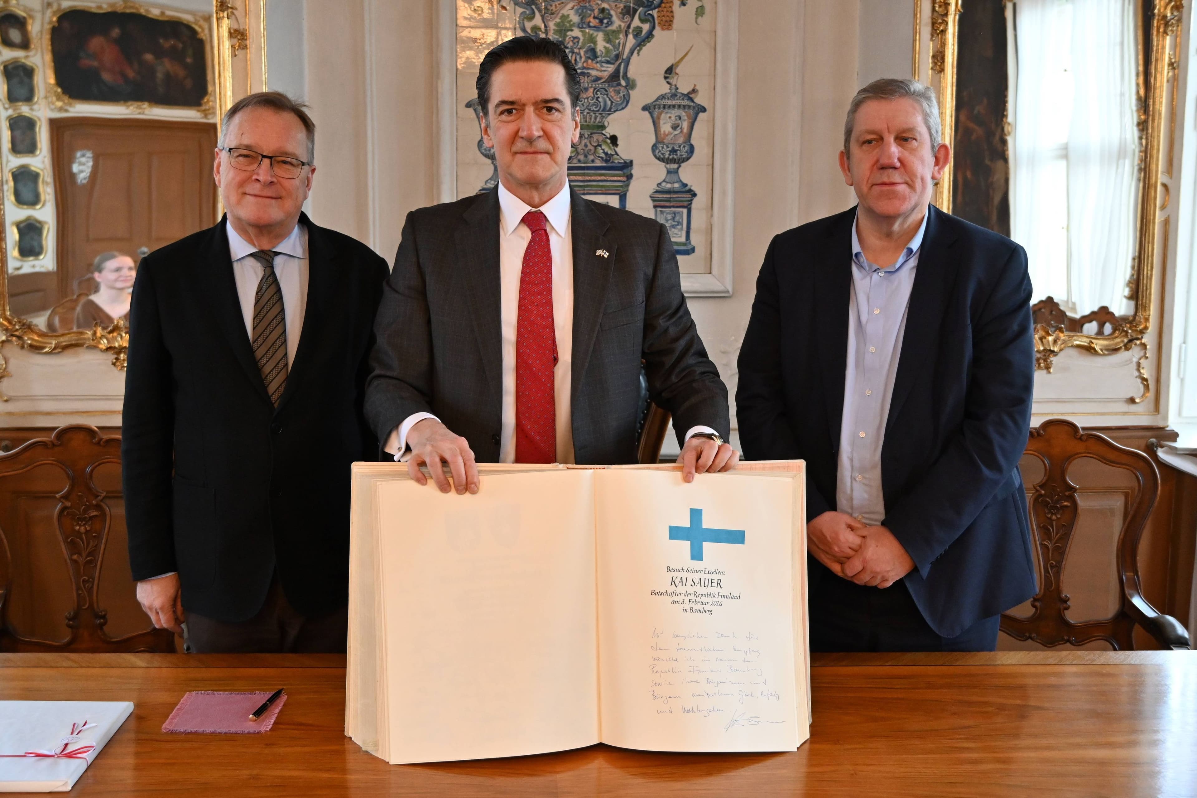 Finnlands Botschafter trägt sich ins Goldene Buch der Stadt Bamberg ein, flankiert von OB Starke und MdB Schwarz.