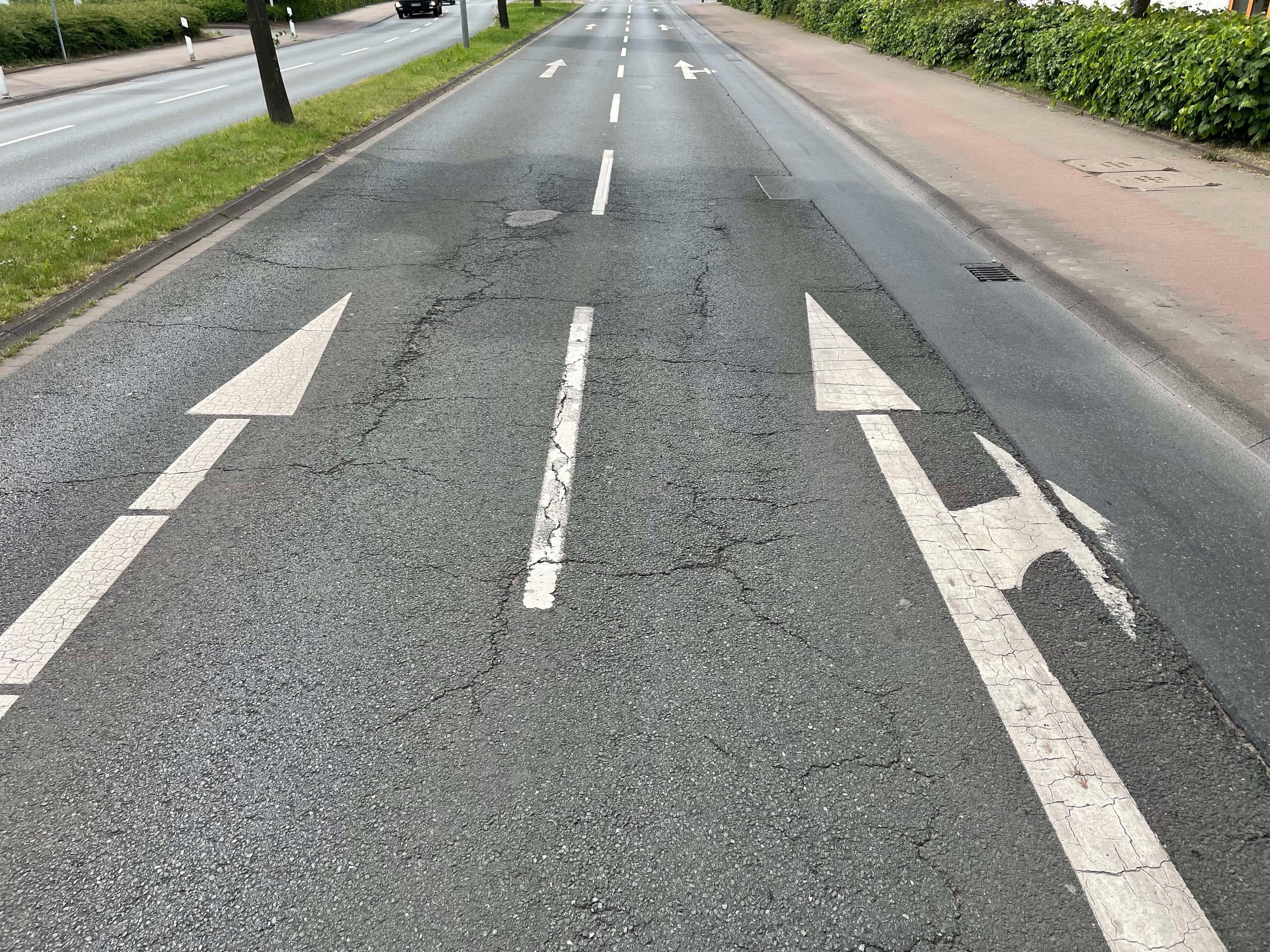 Beschädigte Fahrbahndecke der Ringstraße mit sichtbaren Rissen und Schlaglöchern. Beschädigte Fahrbahndecke der Ringstraße mit sichtbaren Rissen und Schlaglöchern.