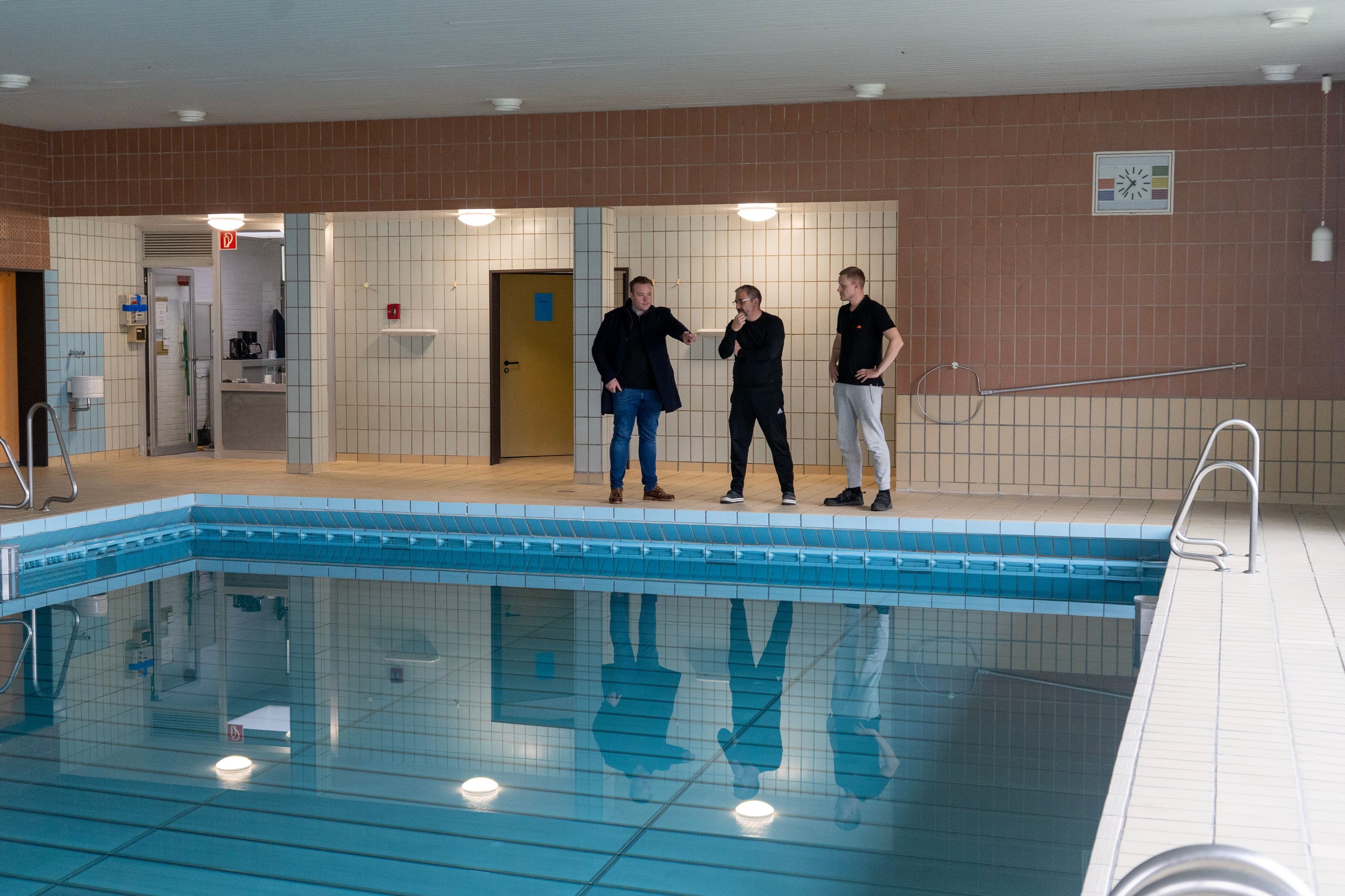 Michael Ruttner, Roberto Krierke und Philip Albert betrachten das Schwimmbecken im Schulzentrum.