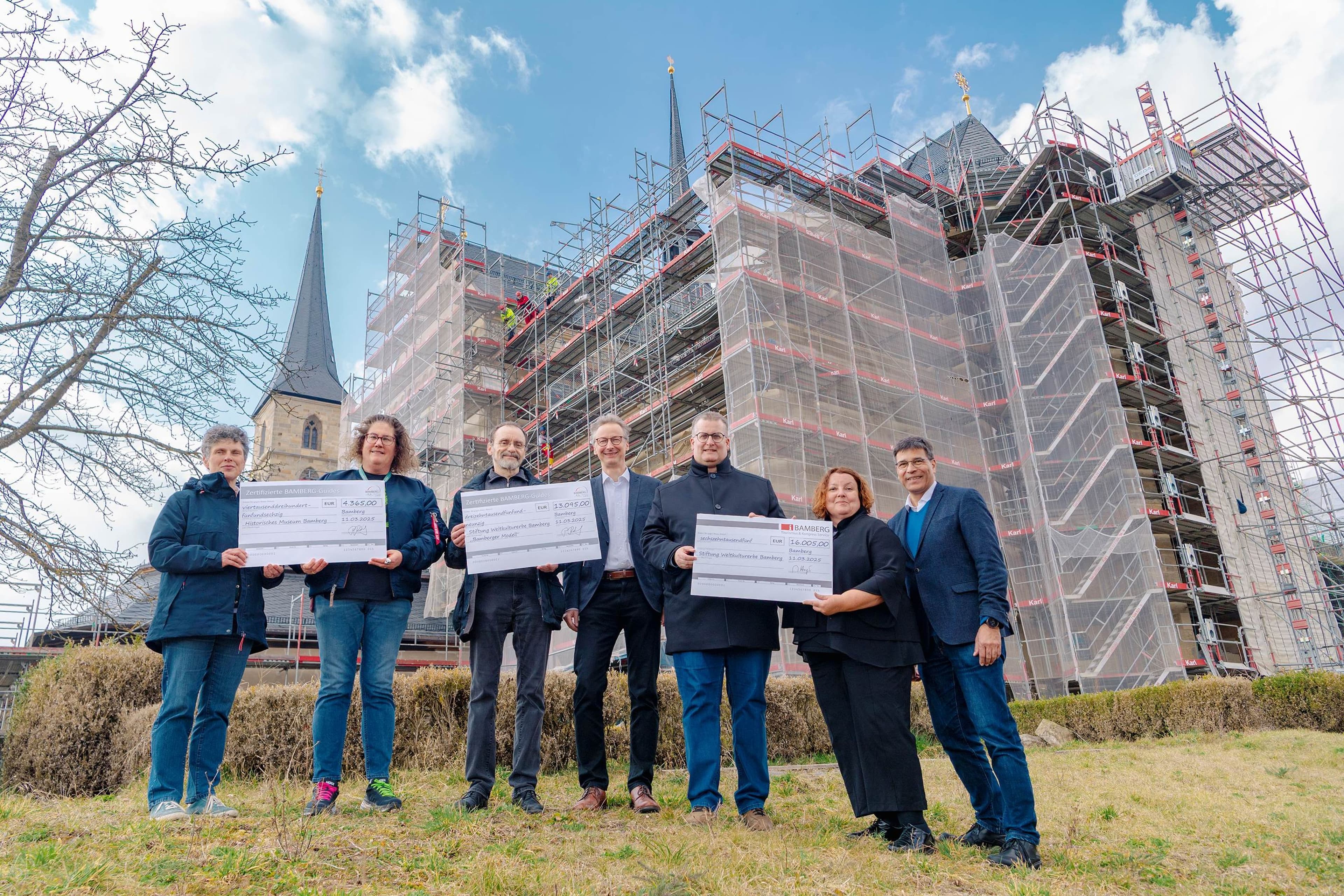 Die Scheckübergabe der Spenden aus den Stadtführungen für die Stiftung Weltkulturerbe Bamberg fand vor dem Kloster St. Michael statt, mit Beteiligung wichtiger Persönlichkeiten der Stadt und der Museen.