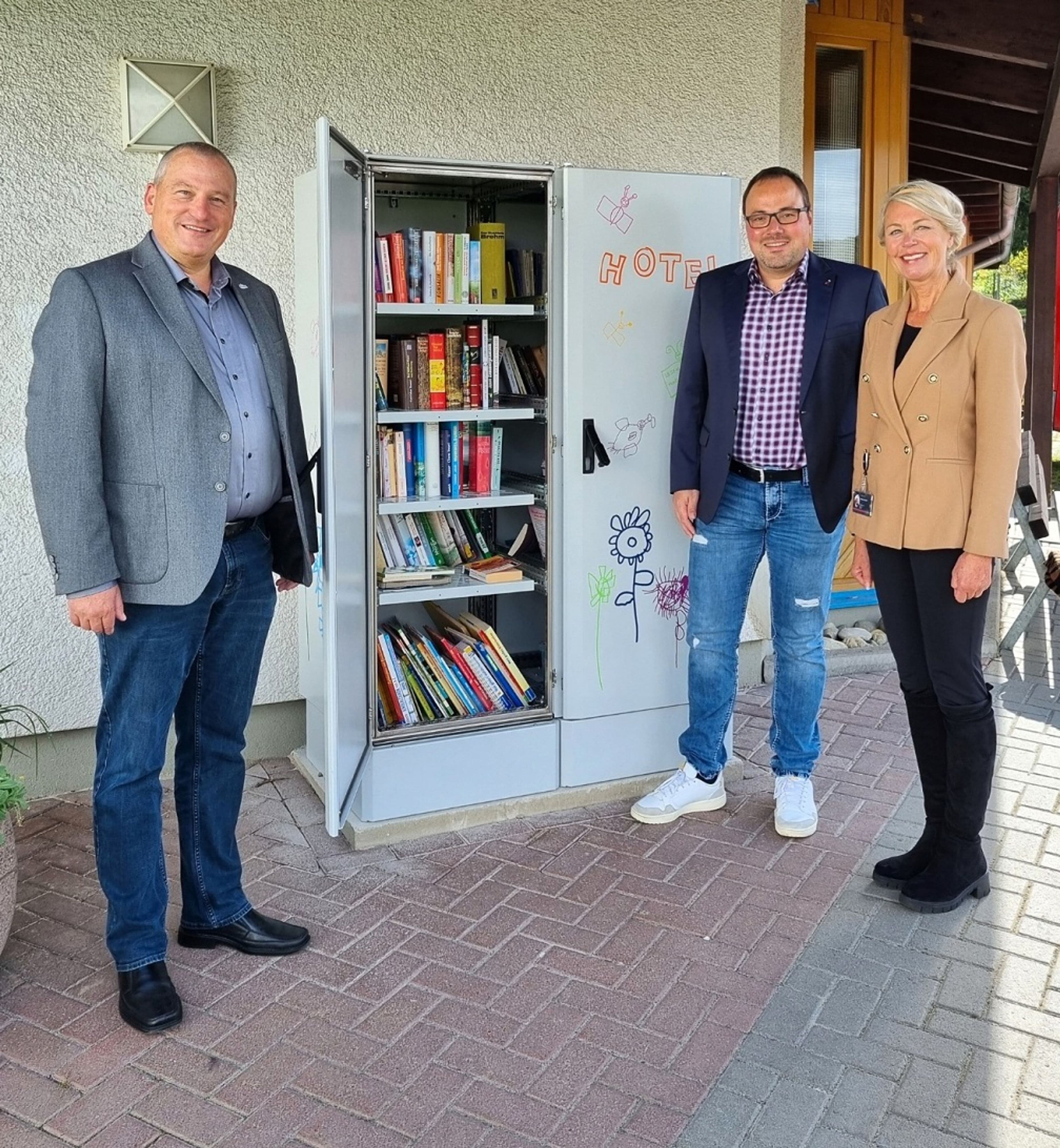 Das Gemeinschaftsprojekt 'Bücherhotel' in Altenkirchen vereint Ordnungs- und Stadtverantwortliche sowie Kinder der Kita 'Speckmäuse', um eine Outdoorbücherei zu gestalten und den Bürgern ein kostenfreies Bücherangebot zu bieten.