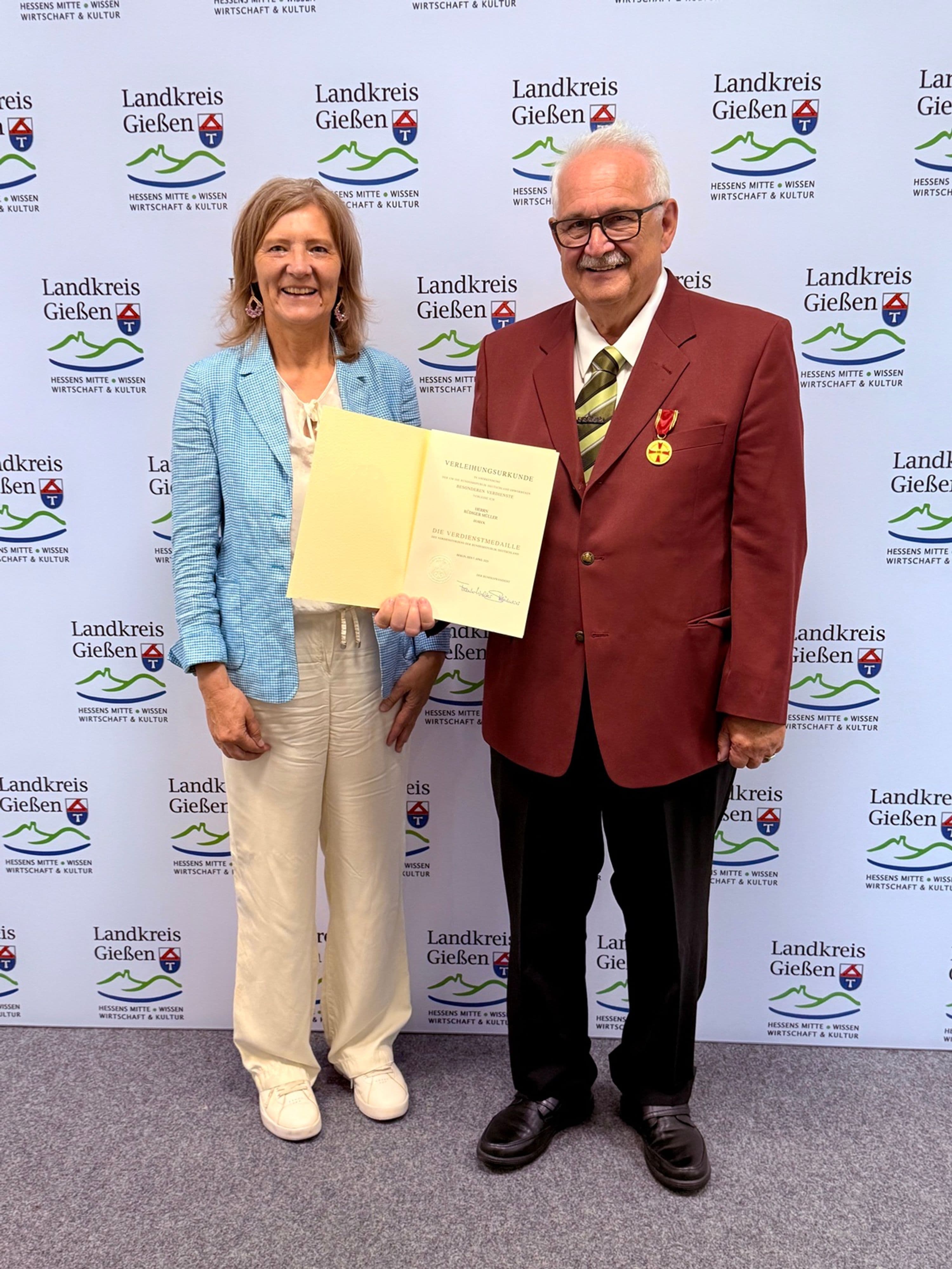 Landrätin Anita Schneider überreicht Rüdiger Müller das Bundesverdienstkreuz für jahrzehntelange Pflegearbeit.