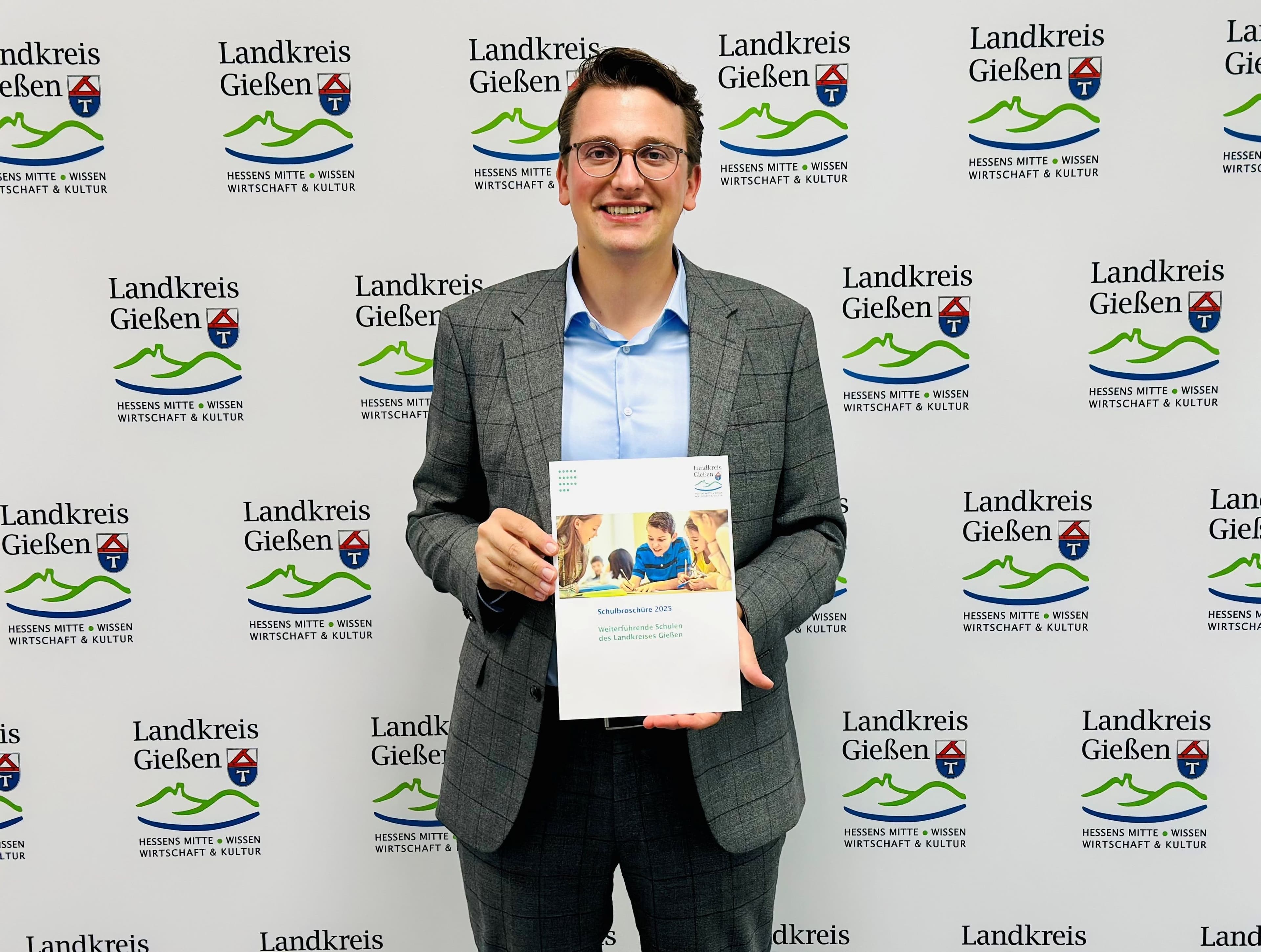 Schuldezernent Christopher Lipp präsentiert die neue Schulbroschüre 2025 für weiterführende Schulen im Landkreis.