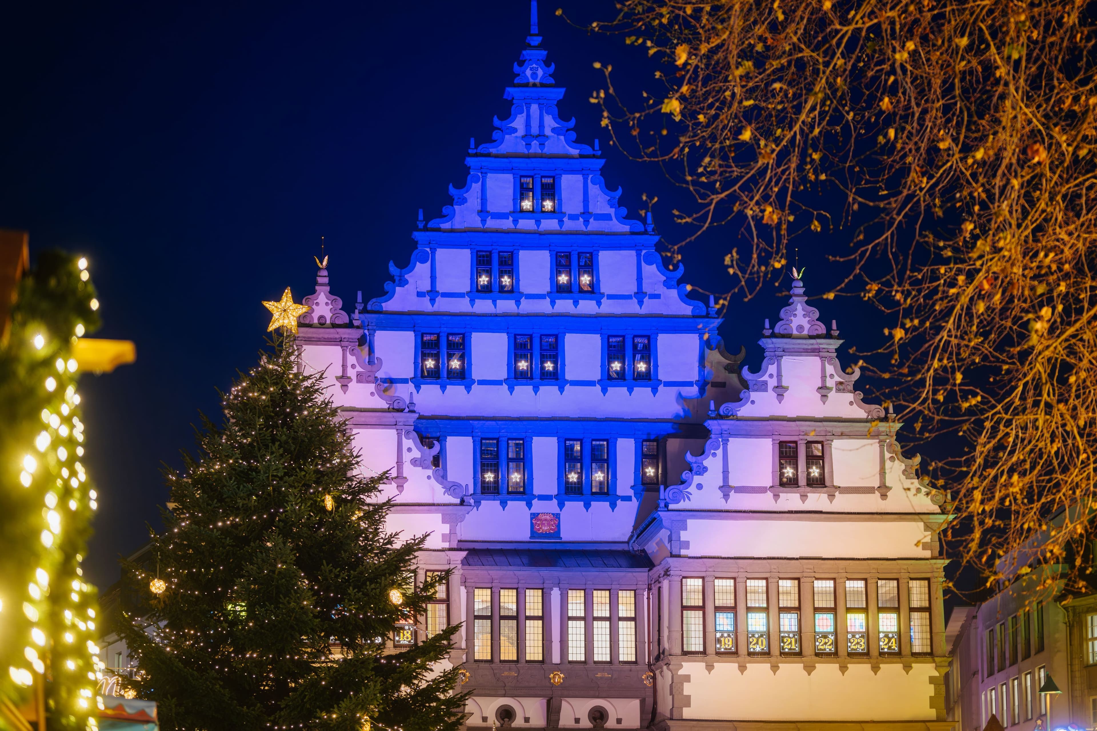 Das Paderborner Rathaus ist in der Weihnachtszeit illuminiert, Adventskalender mit Motiven von Grundschulkindern., Die etwa 20 Meter hohe Weihnachtspyramide ist der Blickfang auf dem Markt- und Domplatz in Paderborn., Rund 20 Kunsthandwerkshütten laden auf dem Weihnachtsmarkt zum Bummeln ein.