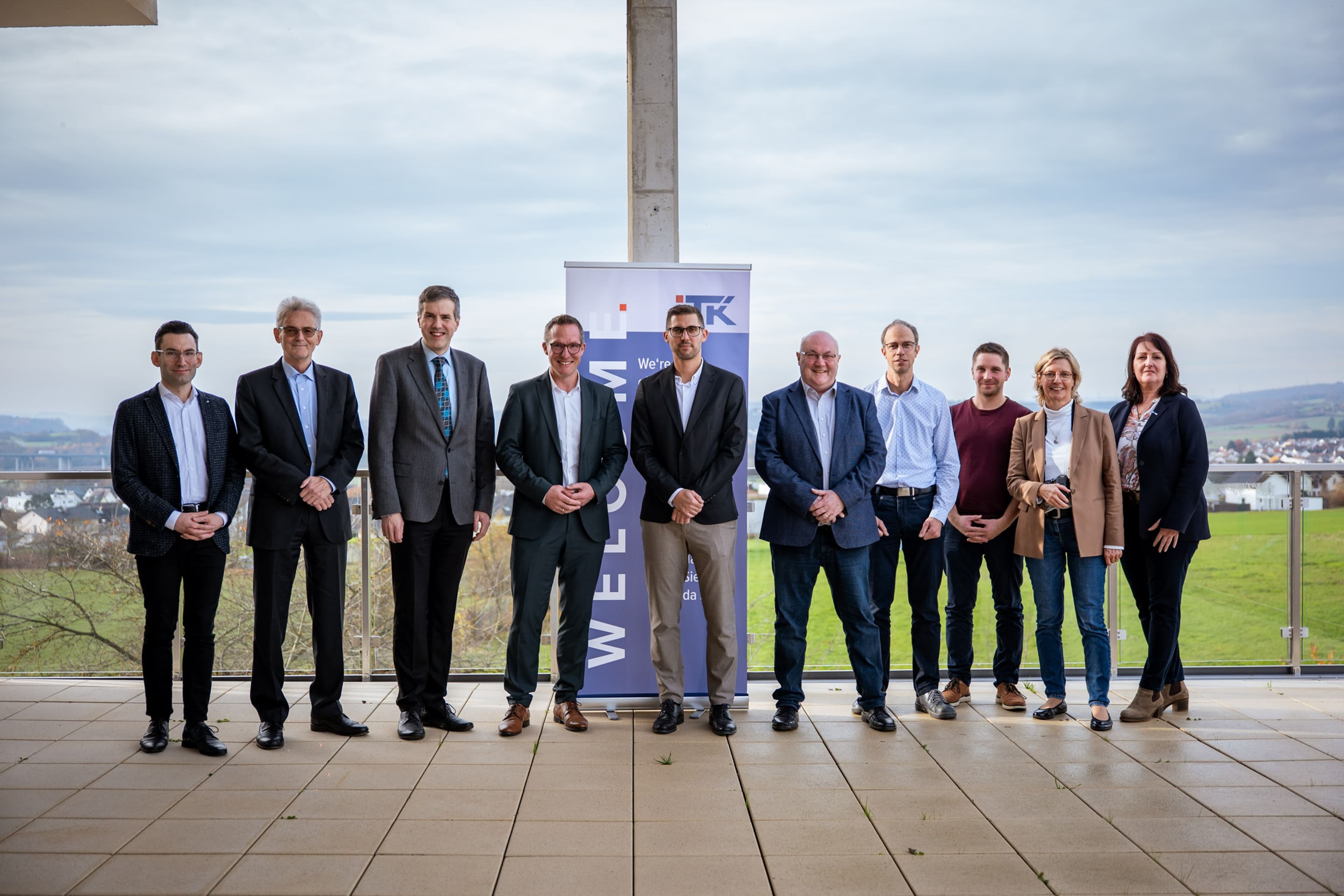 Delegation und Führungskräfte im Gespräch während des Unternehmensbesuchs bei ITK Precisioning GmbH., Prof. Dr. Harald Danne und Carsten Braun erhalten Einblicke in die ITK-Produktion während des Rundgangs., Sebastian Rivera präsentiert im Showroom die Produktvielfalt von ITK.