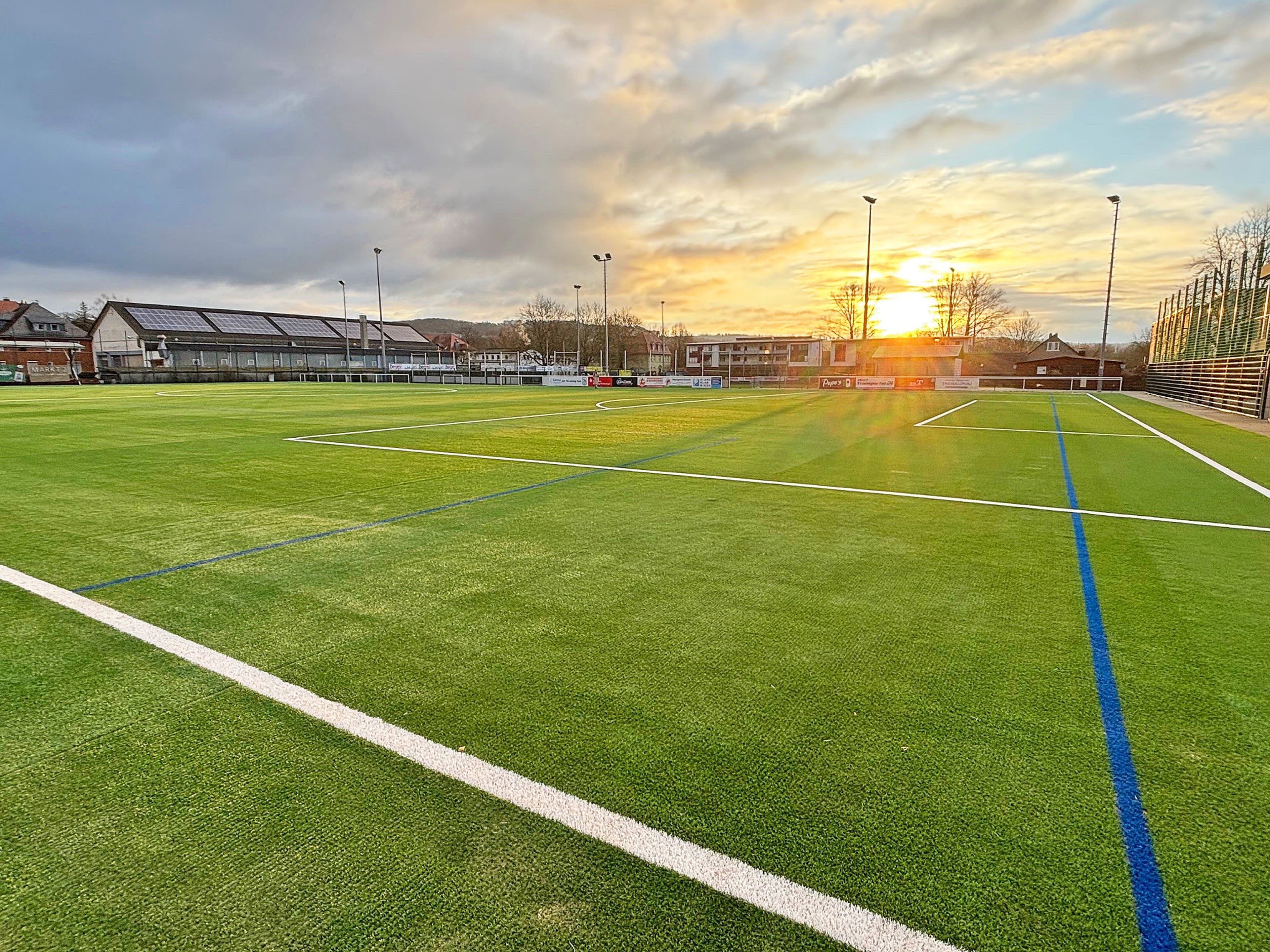 Stadträtin Kirsten Dinnebier, Björn Backes (Fachbereichsleiter Sport, Bäder und Gesundheit) und Janina Acker vom Fachdienst Sport freuen sich über den umfassend sanierten Kunstrasenplatz II im Georg-Gaßmann-Stadion.