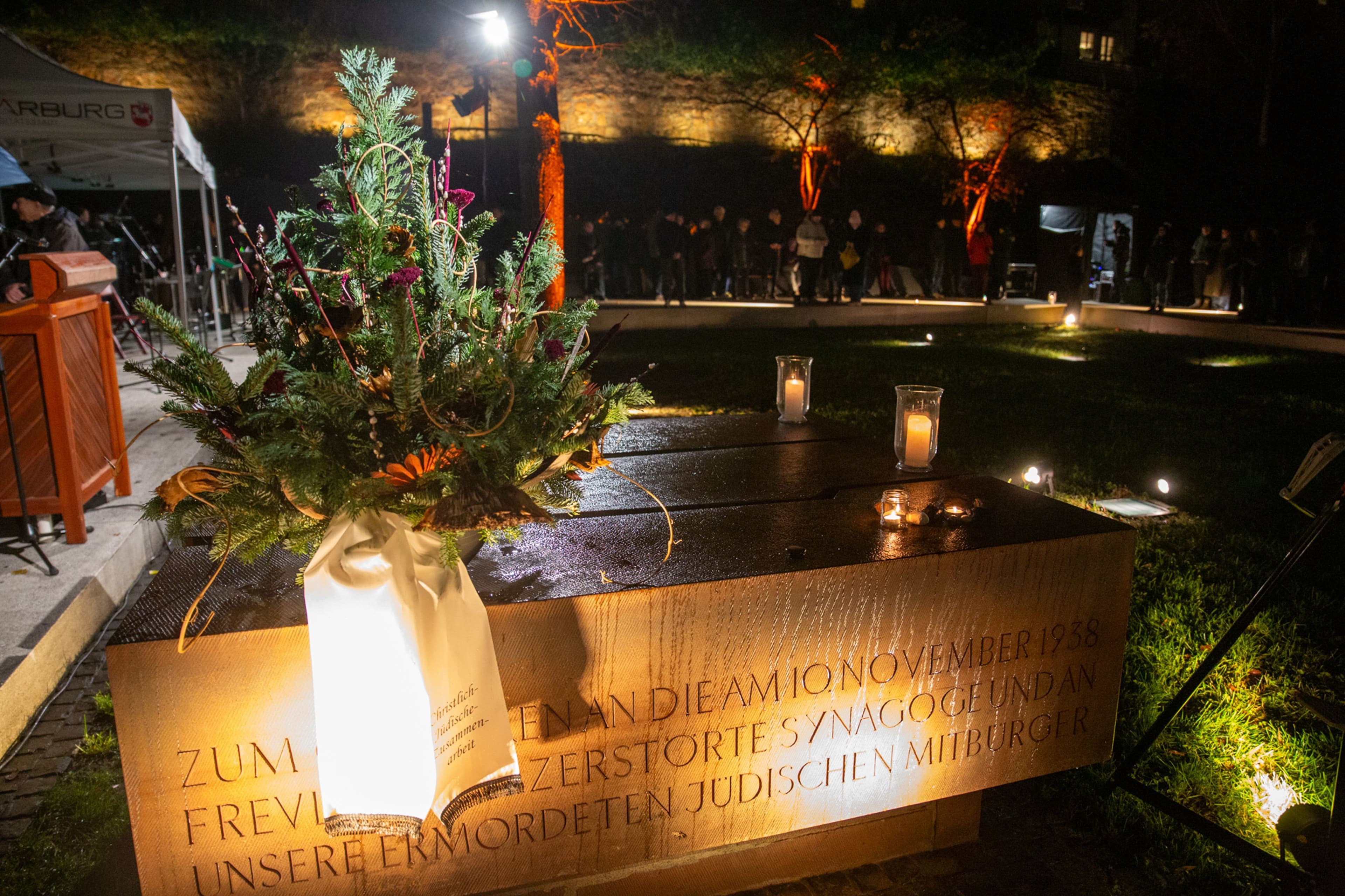 Stadtverordnetenvorsteherin Neuwohner und OB Spies legen zum Gedenken einen Kranz nieder und stellen Kerzen auf.