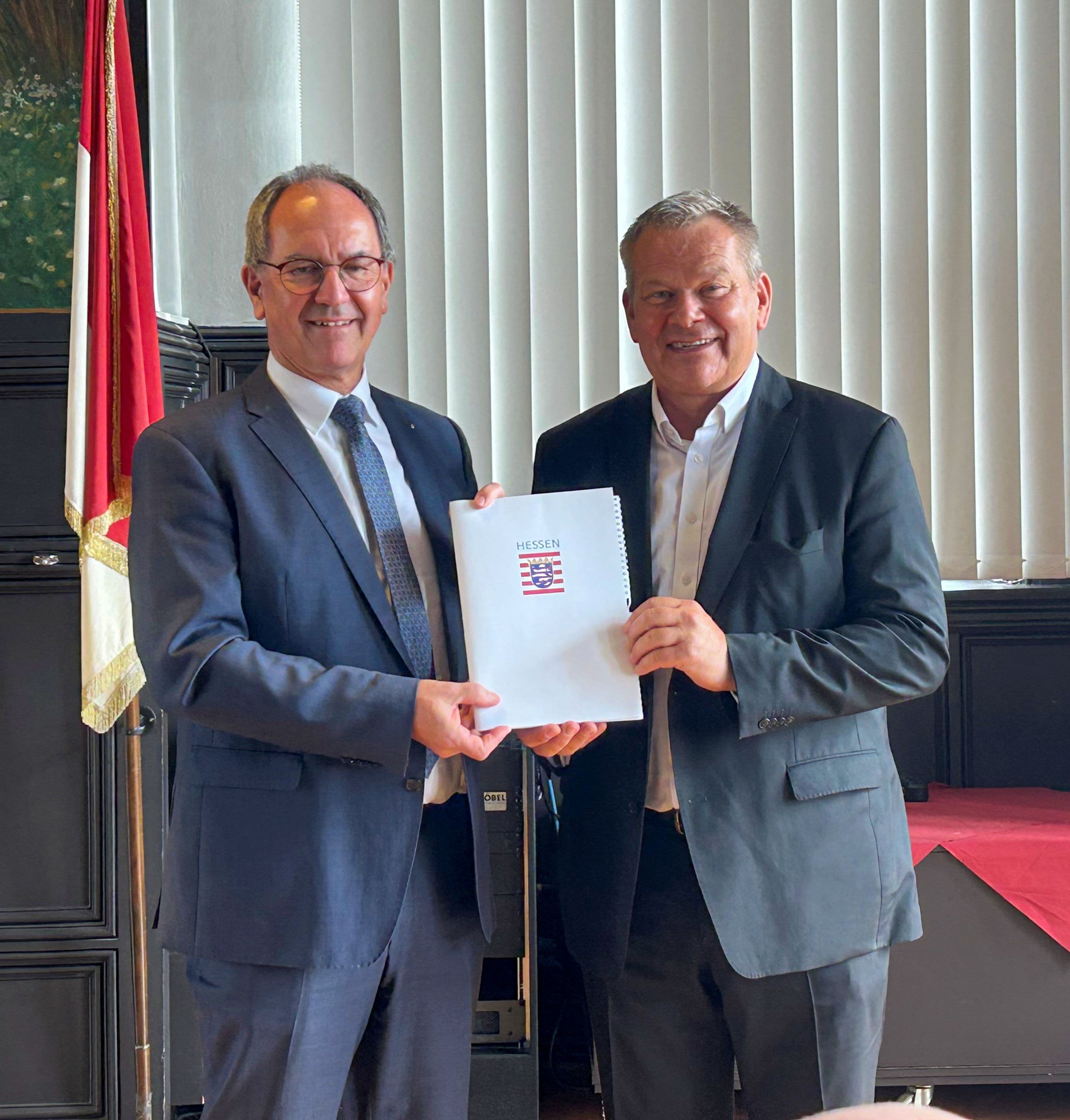 Regierungspräsident Ullrich überreicht Beschluss für Batterieoberleitungsbus an OB Spies.