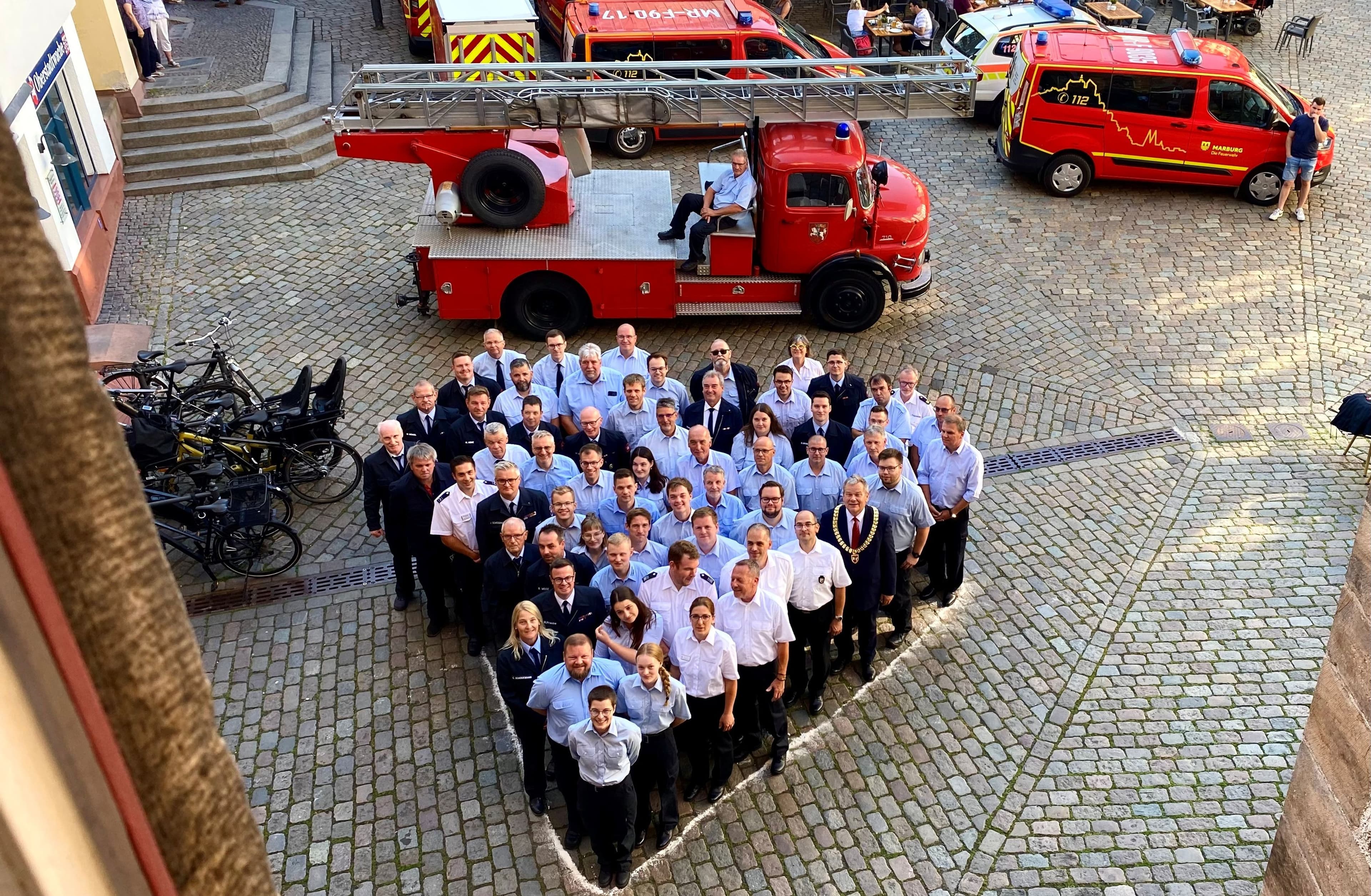 Einsatzkräfte der Feuerwehr Marburg beim Ehrungsabend vor dem Rathaus auf dem Marktplatz.