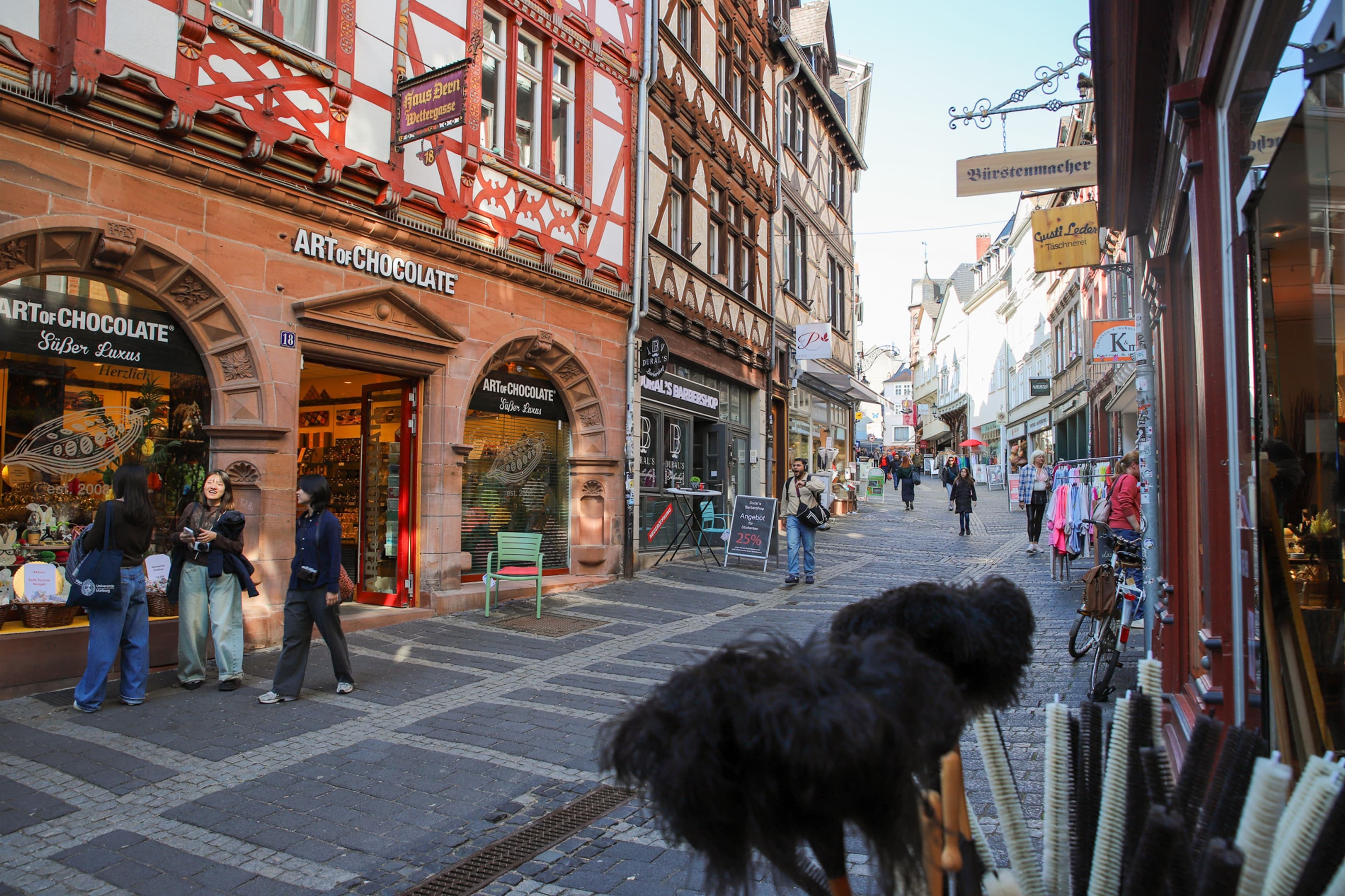 Besucher*innen schlendern durch die Oberstadt von Marburg, die für ihren vielfältigen Einzelhandel bekannt ist. Die Stadt möchte mithilfe einer Online-Befragung mehr über die Wünsche und Erwartungen der Kund*innen erfahren, um die Innenstadt weiter attraktiv zu gestalten.