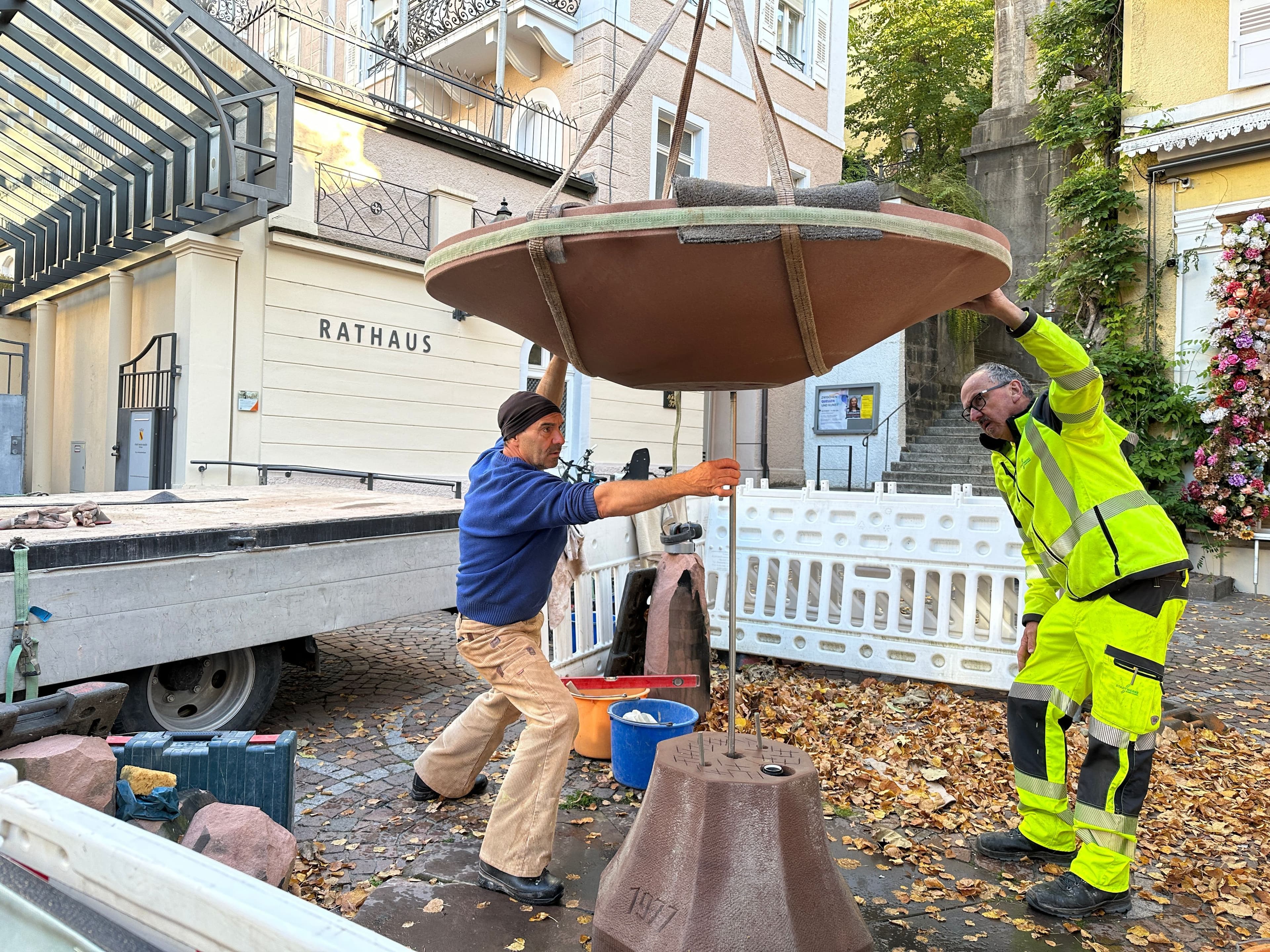 Bildhauer Ralf Schira und Rainer Bisch montieren die neue Brunnenschale am Jesuitenbrunnen.