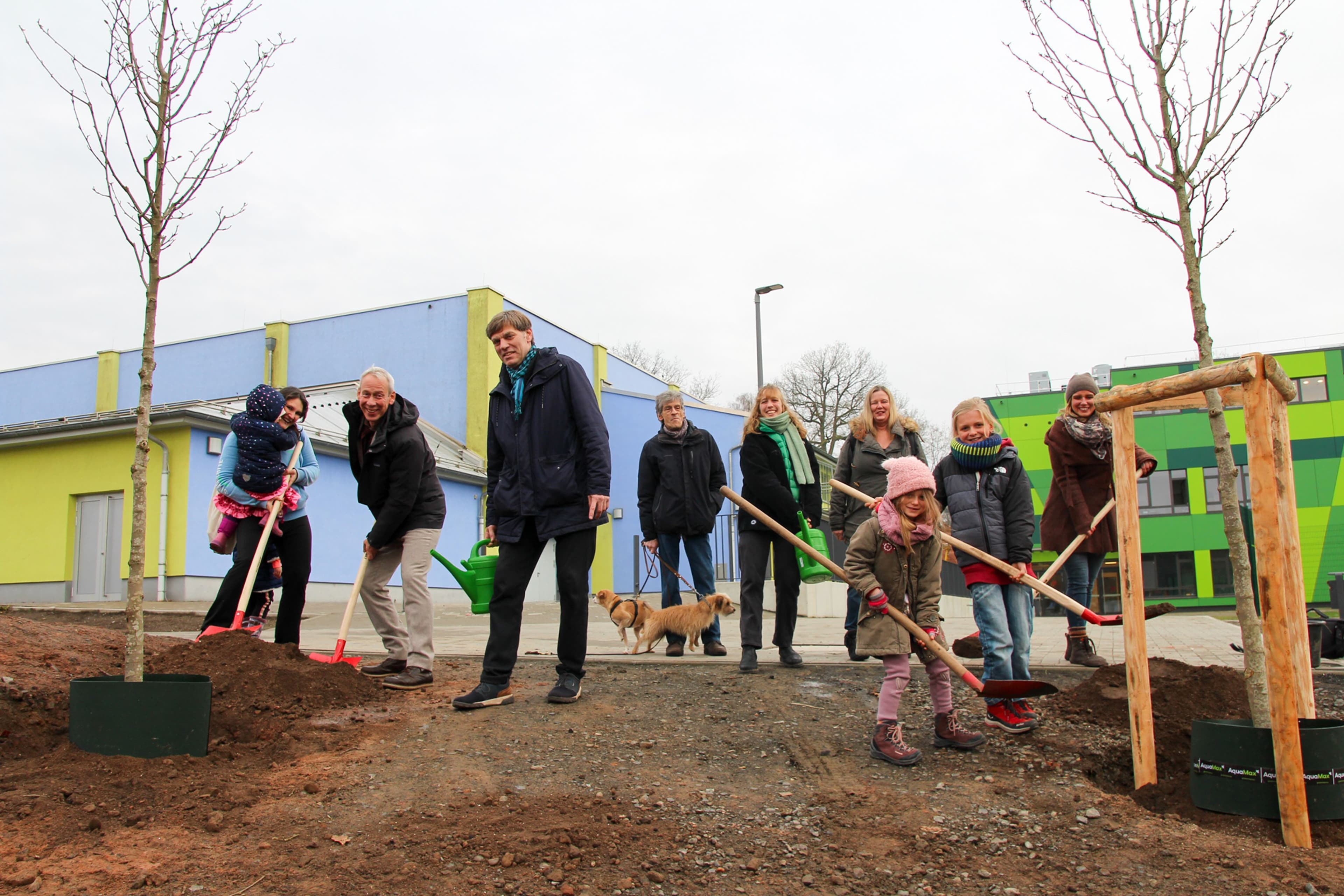 Stadtrat Dr. Kopatz, Oliver Mülders und Mitglieder der Elterninitiative pflanzen Magnolien auf dem Außengelände der Richtsberg-Gesamtschule.