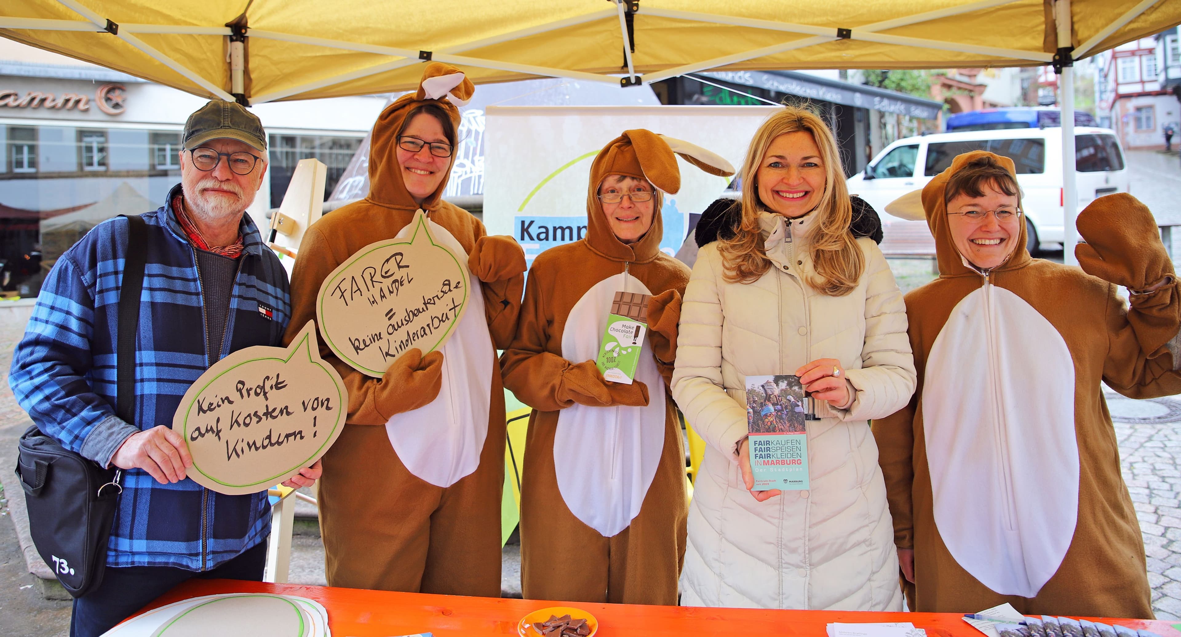 Fairtrade-Osteraktion mit Infostand auf dem Marburger Marktplatz, Mitglieder der Steuerungsgruppen als Osterhasen verkleidet.