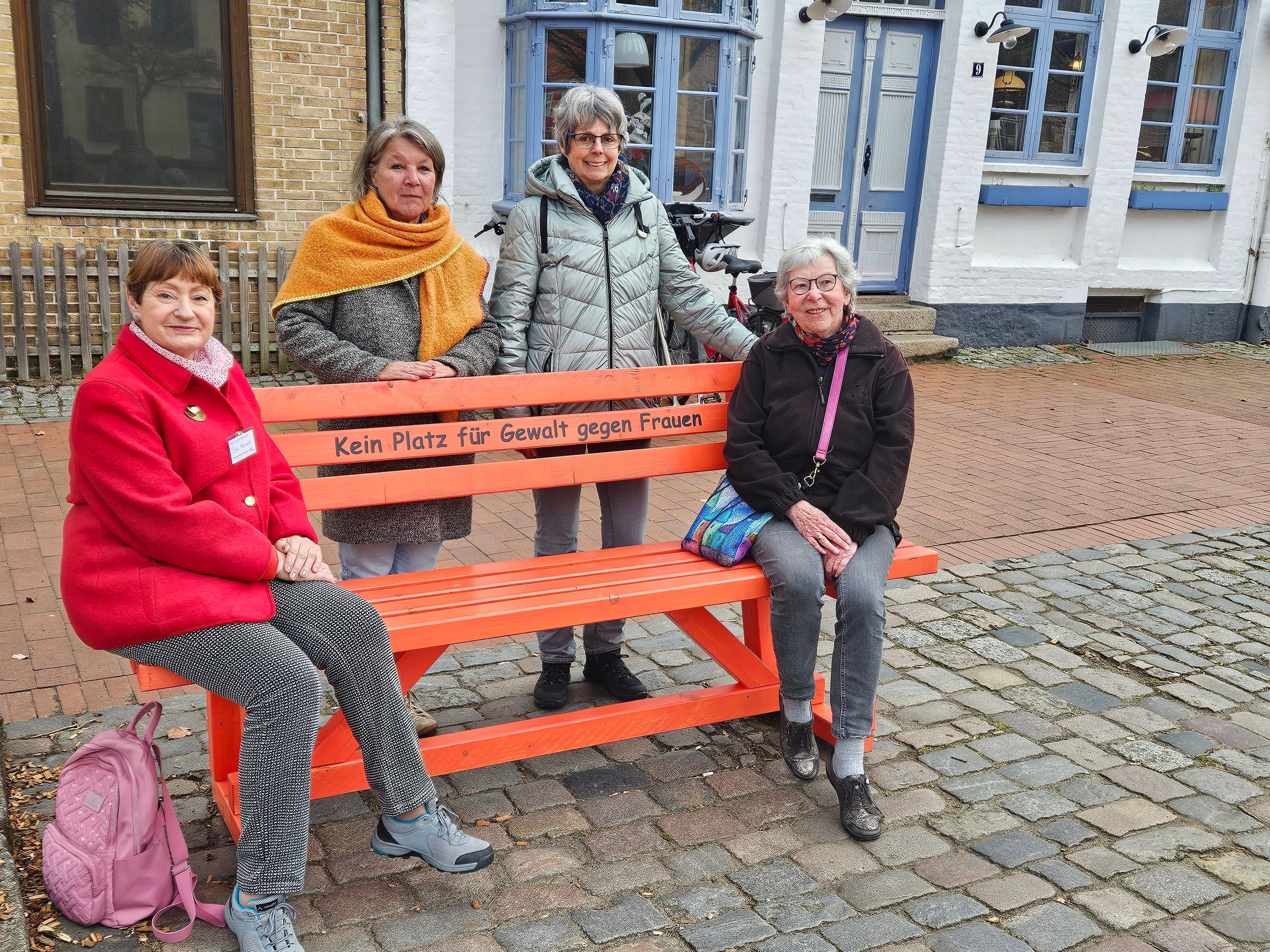 Orangefarbene Bank am Rathausmarkt Schleswig setzt Zeichen gegen Gewalt an Frauen und Mädchen.