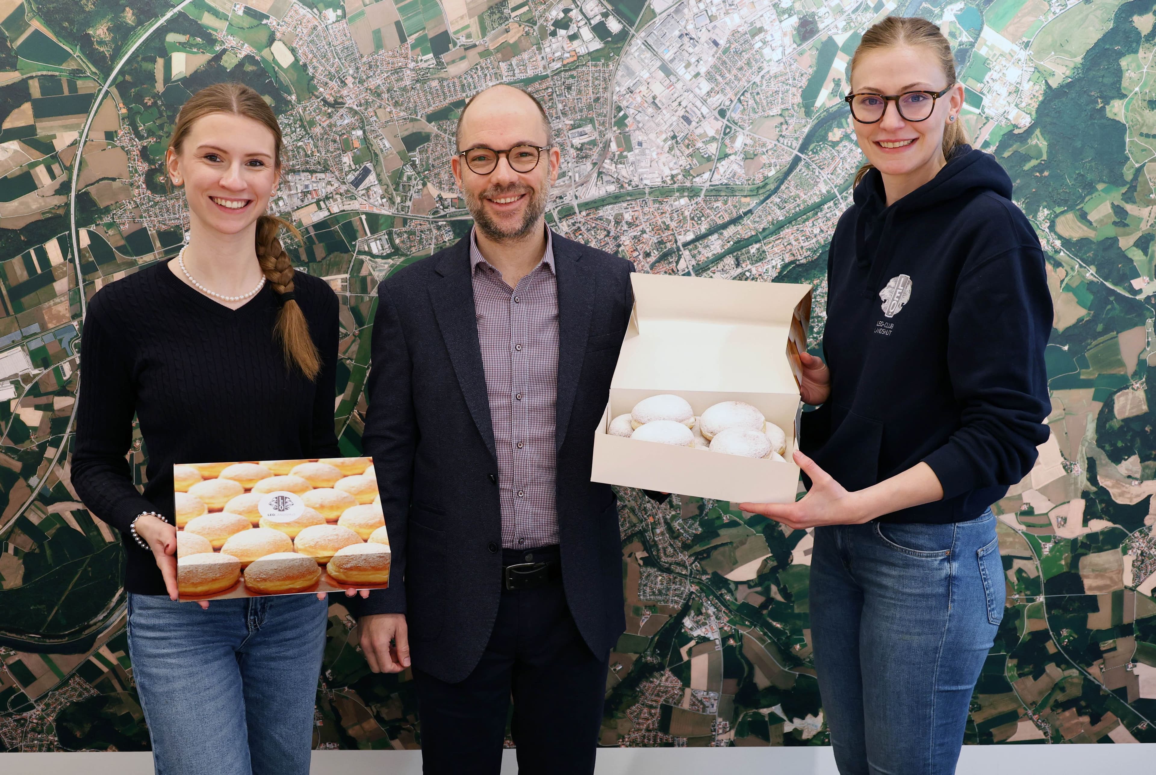 Elisabeth Kortmann und Elena Sutor übergeben Krapfen an Klaus Peißinger im Rathaus Landshut.