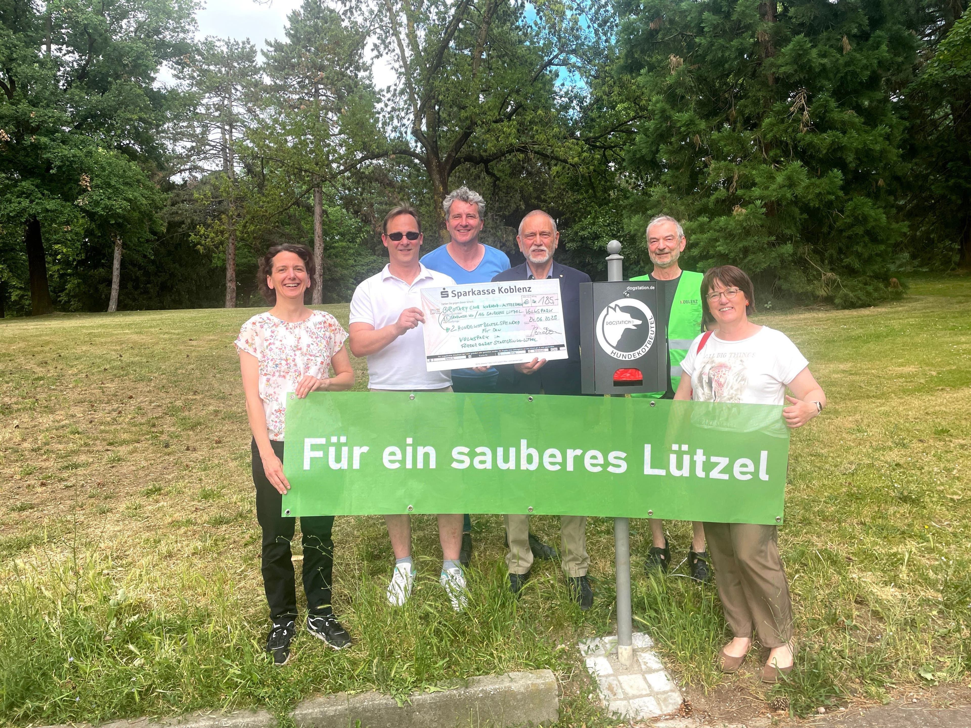 Personen verschiedener Initiativen präsentieren die neuen Hundekotbeutelstationen im Lützeler Volkspark.