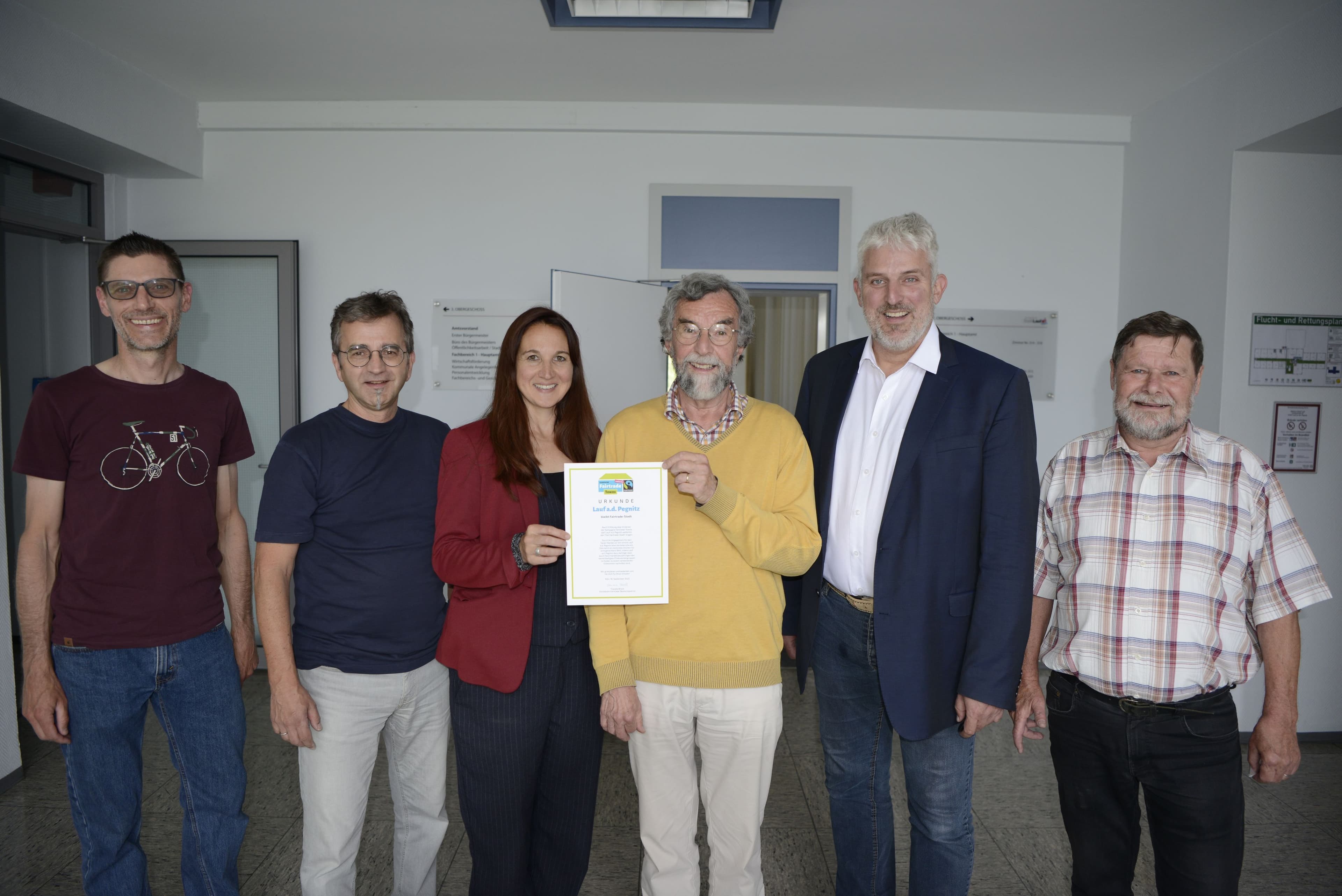 Mitglieder der Steuerungsgruppe Fairtrade Town im Rathaus Lauf mit der erneuerten Urkunde.