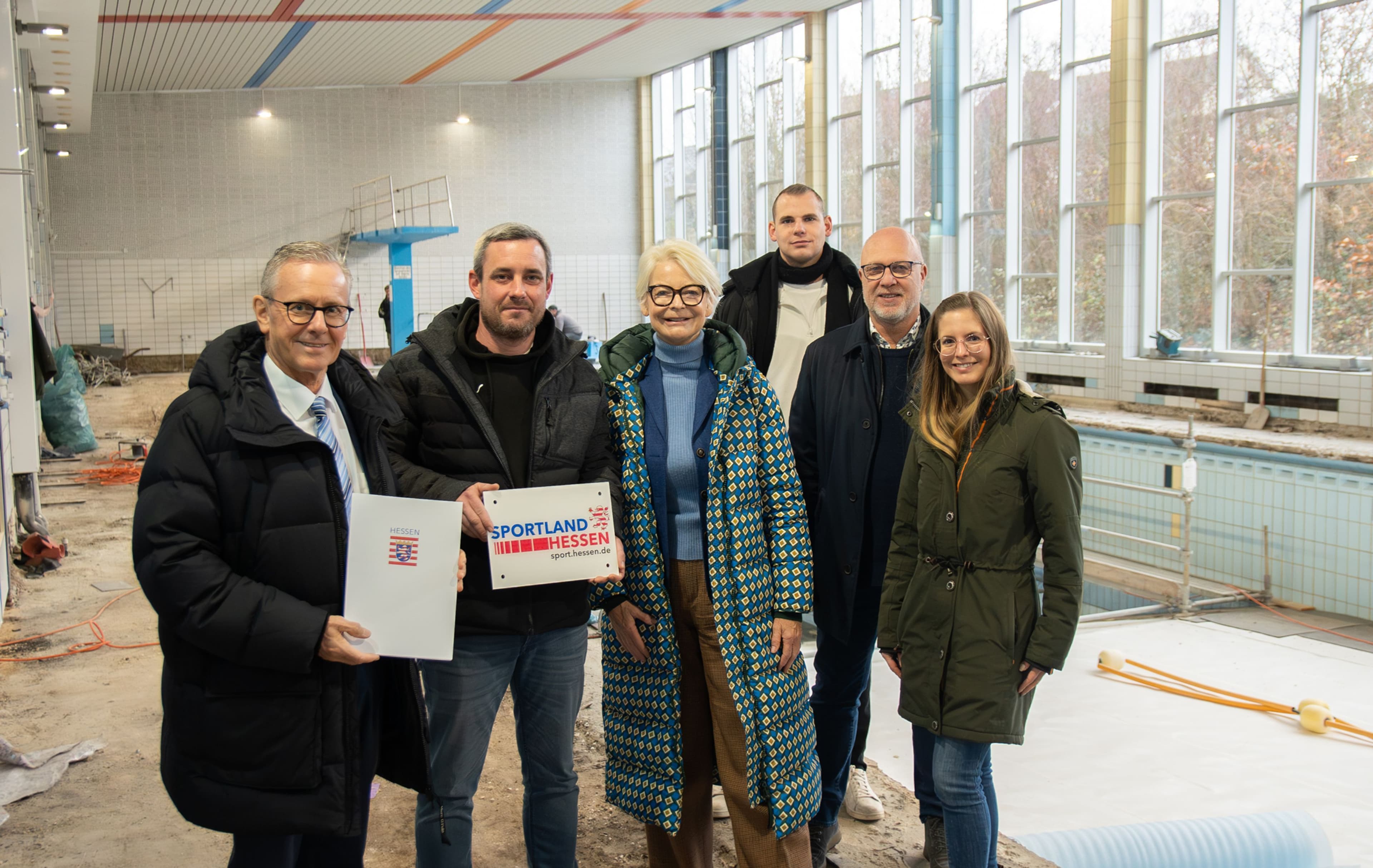 Ann-Kathrin Linsenhoff überreicht den Förderbescheid für "SWIMplus" an Bürgermeister Mario Schramm und weitere Beteiligte.